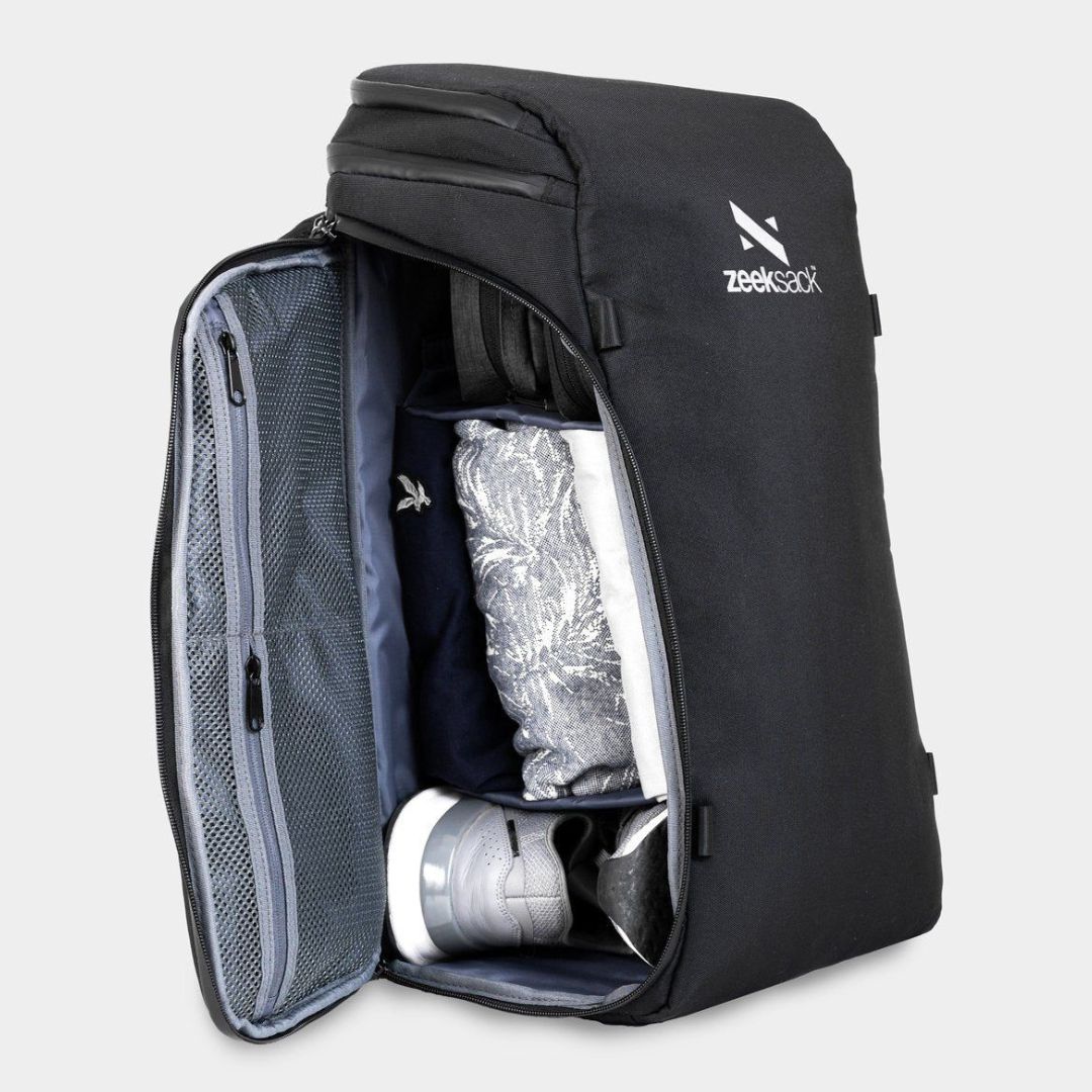 En svart ryggsäck som är öppnad från sidan, fylld med skor och kläder.