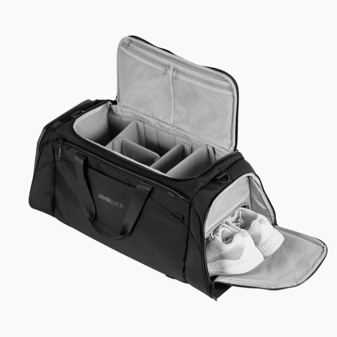 En svart duffelbag med organiserade fack och separat skofack med vita skor.