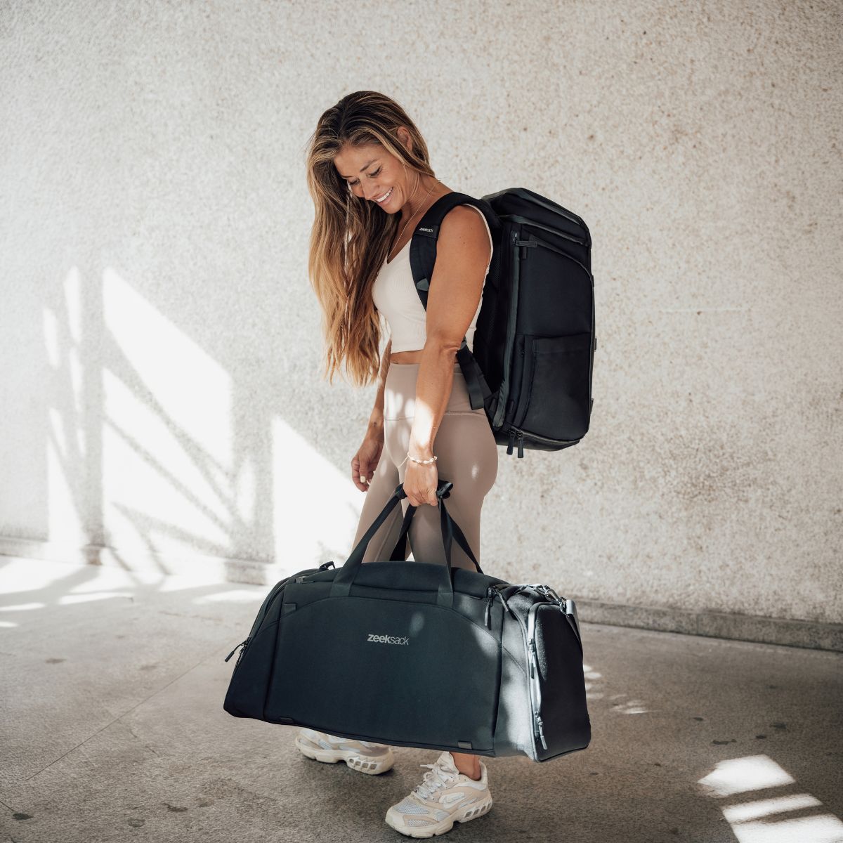 Zeeksack - Kvinna med The Organizer 30L på ryggen och The Weekender 50L i handen.