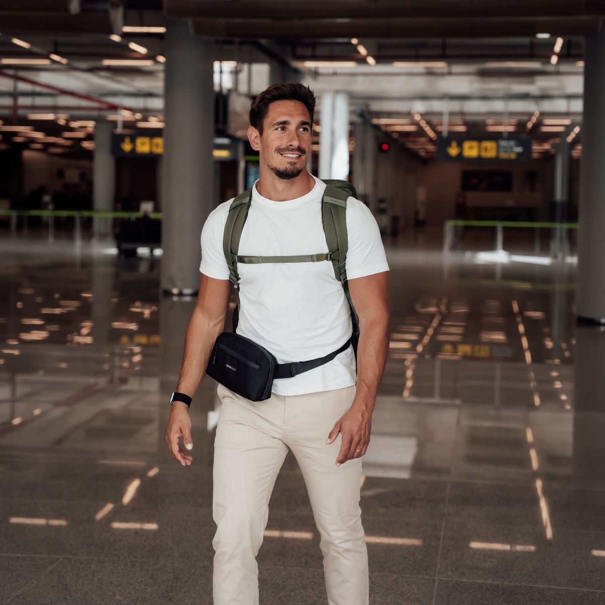 Zeeksack - Man med The Underseat 15L på ryggen och Crossbody Organizer runt midjan på en flygplats.