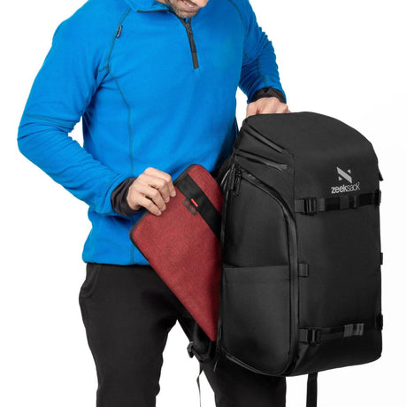 Man håller i svart ryggsäck och lägger i en laptop i laptopfacket. 