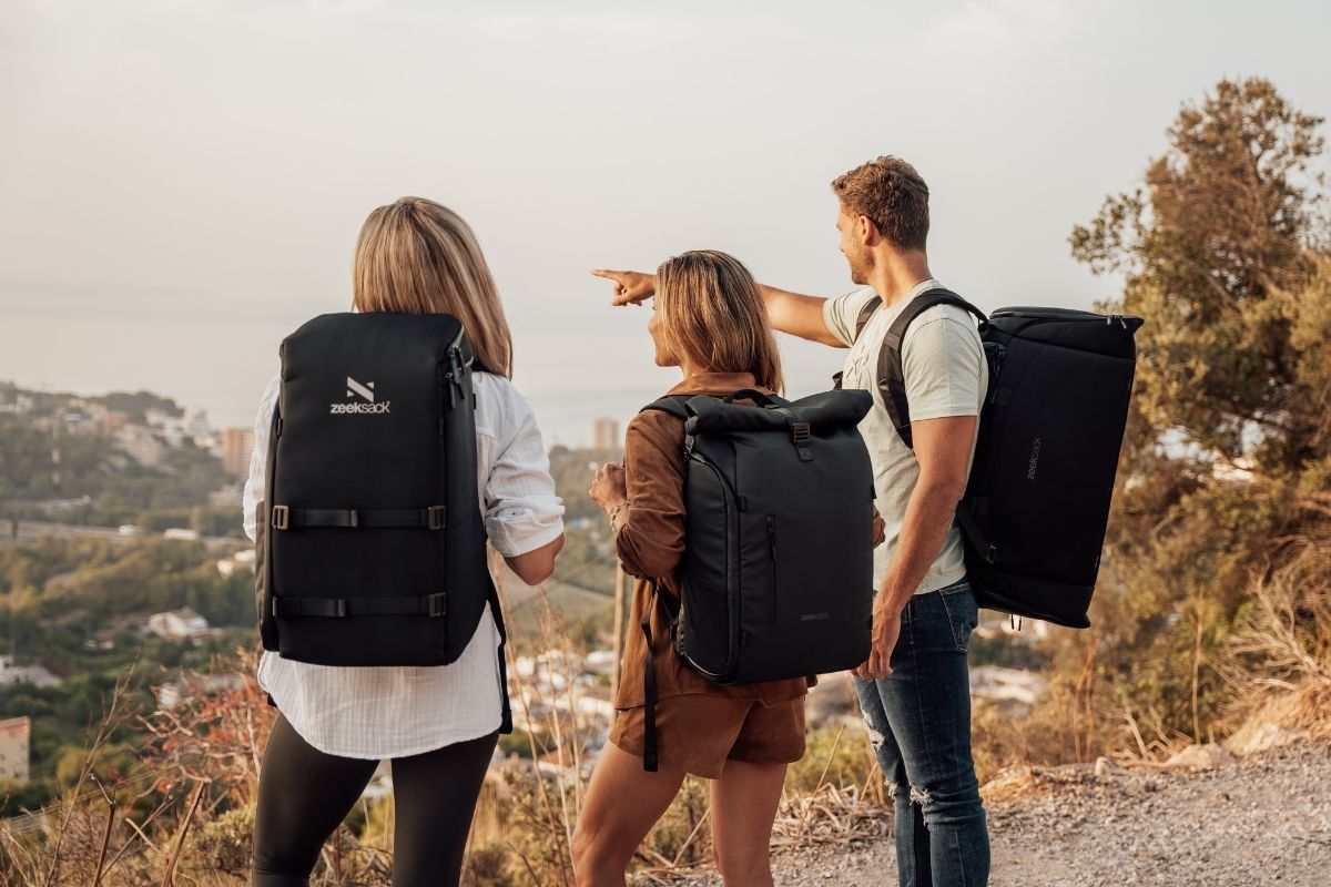två kvinnor och en man med ryggsäckar från zeeksack vid en utsiktsplats