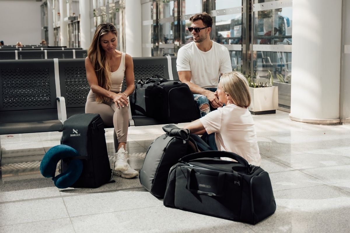 två kvinnor och en man sitter på flygplatsen med väskor och ryggsäckar från Zeeksack